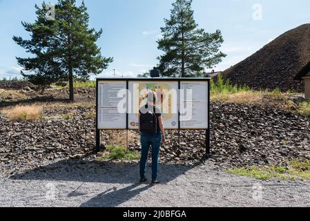 Falun, Dalarna - Schweden - 08 05 2019 Touristen, die die Falun-Kupfermine besuchen, betrachten ein Hinweisschild Stockfoto