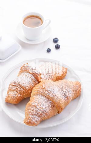 Paar Croissants auf einem weißen Teller mit Kaffee und Beeren. Selektiver Fokus Stockfoto