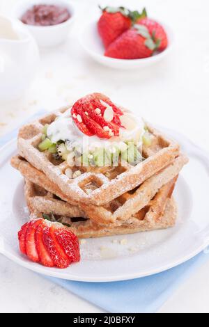 Waffeln mit Vollkornmehl und Früchten auf einem weißen Teller auf einer blauen Serviette Stockfoto