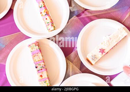 Kleine Scheiben Geburtstagskuchen auf weißem Papier Platten. Stockfoto