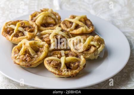 Kleine Apfelkuchen mit Zimt- und Teigdekoration auf einem Teller - Apfeltörtchen schließen mit selektivem Fokus Stockfoto