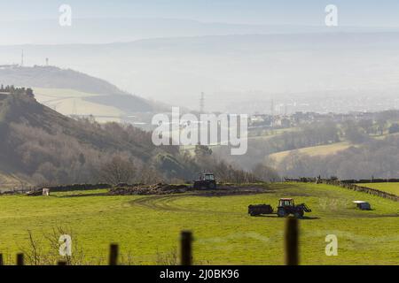 Halifax, West Yorkshire, Großbritannien. 17.. März 2022. Wetter in Großbritannien. Ein Frost über Nacht ging einem wunderschönen blauen Himmel in Halifax, West Yorkshire, Großbritannien, nach. Im Shibden-Tal bereitet ein Bauer seine Felder für die kommende Saison vor, um das Gras zu füttern. Das Shibden-Tal ist bekannt als die ehemalige Heimat von Anne Lister, die in der Fernsehproduktion Gentleman Jack serialisiert wurde. Kredit: Windmill Images/Alamy Live Nachrichten Stockfoto