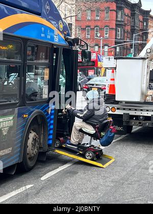 Behinderter Mann in einem Rollstuhl steigt in einen Bus auf der 7th Avenue in Brooklyn, Newe York. Stockfoto