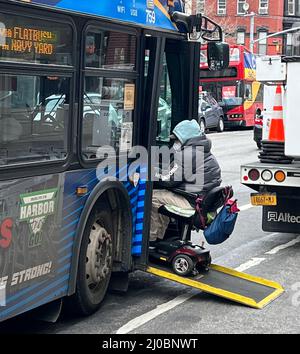 Behinderter Mann in einem Rollstuhl geht in einen Bus auf der 7. Avenue in Brooklyn, Newe York. Stockfoto