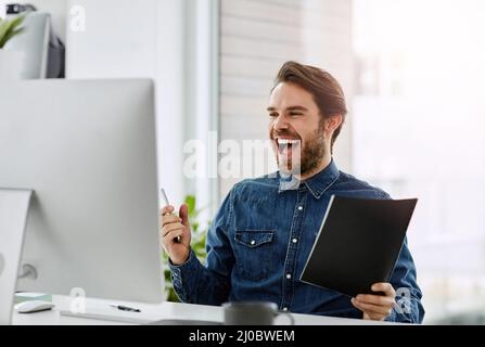 Es ist ein Jackpot. Eine kleine Aufnahme eines hübschen jungen Geschäftsmanns, der in seinem Büro jubelt. Stockfoto