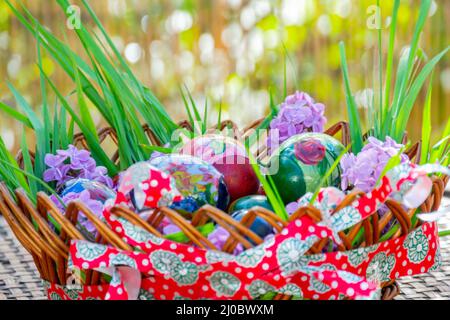 Gestreifter Korb voller Osterschmuck, der auf einem Holztisch steht Stockfoto
