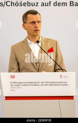 Cottbus, Deutschland. 18. März 2022. Holger Kelch, Oberbürgermeister der Stadt Cottbus, grüßt bei der Eröffnung der Infopunkt des Cottbuser Eisenbahnwerks auf dem Vorplatz des Cottbuser Hauptbahnhofs. Am Cottbus Hauptbahnhof wurde heute eine Informationsstelle des Cottbuser Eisenbahnwerks eröffnet. Die ersten ICE-Züge werden ab 2024 im derzeit im Bau befindlichen Bahnwerk gewartet. Quelle: Frank Hammerschmidt/dpa/Alamy Live News Stockfoto