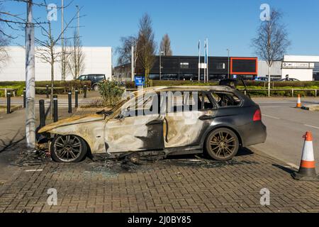 Ein ausgebranntes BMW-Auto auf einem Supermarkt-Parkplatz. Stockfoto