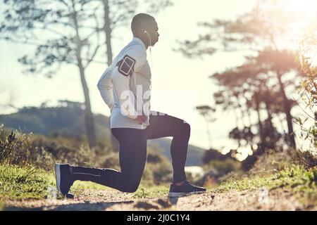 Hes ernst über Fitness. Ganzkörperaufnahme eines hübschen jungen Mannes, der sich vor dem Training im Freien dehnt. Stockfoto