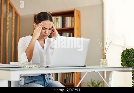 Dies war der schlimmste Tag aller Zeiten. Aufnahme einer jungen Geschäftsfrau, die bei der Arbeit von zu Hause aus Kopfschmerzen hat. Stockfoto