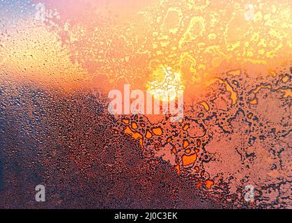 Natur Hintergrund mit Eis Muster, helles Sonnenlicht und Wasser Tropfen auf Winter Fenster Glas Stockfoto