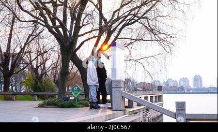 Ein Paar mit Gesichtsmasken gesehen Blick auf eine Karte in einem Park mit Sonnenuntergang im Hintergrund. Suzhou ist eine Stadt, die 100 km von Shanghai entfernt liegt. Die Stadt befindet sich seit Ende Februar in Quarantäne, nachdem neue Fälle von Covid 19 entdeckt wurden. Stockfoto