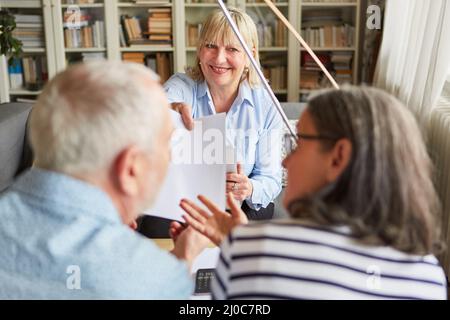 Finanzberater, der einem älteren Paar einen Vertrag oder eine Form für Altersvorsorge gibt Stockfoto