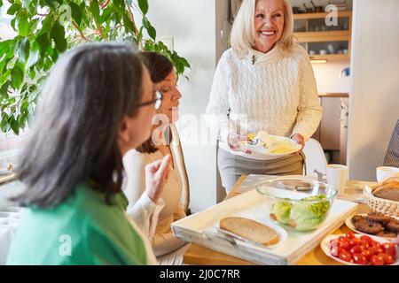 Gruppe älterer Frauen, die gemeinsam in der Küche am Tisch brunchen oder frühstücken Stockfoto