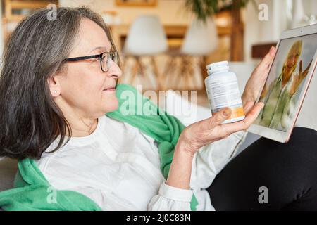 Arzt und ältere Frau, die zu Hause auf dem Tablet-Computer eine Videokonsultation in Telemedizin durchführen Stockfoto