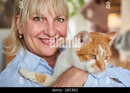 Ältere Frau, die zu Hause eine Katze in den Armen hält, als Konzept der Tierliebe und -Kameradschaft Stockfoto