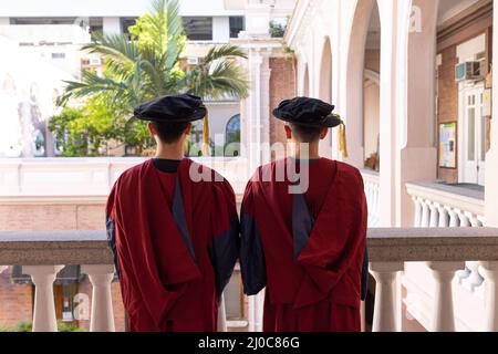 Zwei glückliche stolze Doktoranden graduierten männliche Studenten in akademischem Kleid. Rückansicht Stockfoto