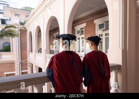 Zwei glückliche stolze Doktoranden graduierten männliche Studenten in akademischem Kleid. Rückansicht Stockfoto