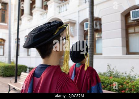 Zwei glückliche stolze Doktoranden graduierten männliche Studenten in akademischem Kleid. Rückansicht Stockfoto