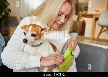 Ältere Frau mit kleinem Hund, der in ihrer leeren Brieftasche als Altersarmut-Konzept besorgt aussieht Stockfoto