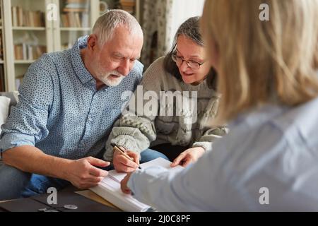 Seniorenpaar unterzeichnet einen Vertrag oder eine Vollmacht oder füllt einen Antrag aus Stockfoto