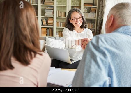 Senioren und ein Steuerberater geben nach erfolgreicher Beratung oder Vertragsabschluss einen Handschlag Stockfoto