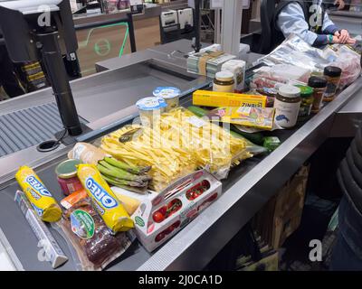 Karlsruhe, Deutschland - 12. März 2022: Kassierer im Hintergrund mit mehreren Lebensmittelbonbons Gemüseobst Konfitüren auf der Theke im Supermarkt-Supermarkt Stockfoto