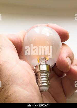 POV-Außenhandgriff mit neuer LED-E14-Glühlampe in der Hand Stockfoto