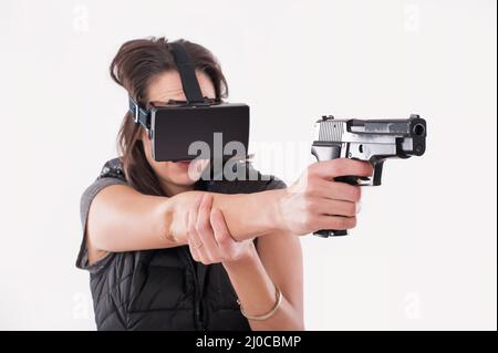 Frau spielen VR-Shooter-Spiel mit VR-Brille und Pistole. Studioaufnahmen Stockfoto