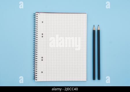 Nahaufnahme des leeren Notizbuches mit Bleistiften auf blauem Hintergrund. Stockfoto