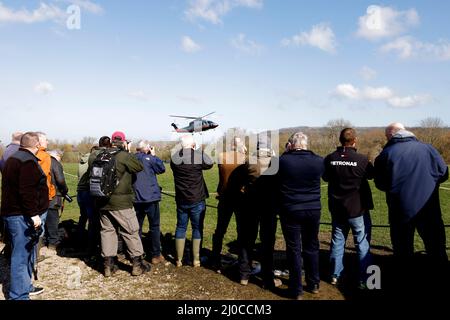 Rennfahrer fotografieren während des vierten Tages des Cheltenham Festivals auf der Pferderennbahn von Cheltenham einen Hubschrauber, der auf dem Kurs landet. Bilddatum: Freitag, 18. März 2022. Stockfoto