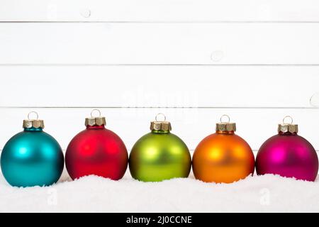Weihnachten bunte Weihnachtskugeln in einer Reihe hölzernen Hintergrund Dekoration Schnee Stockfoto