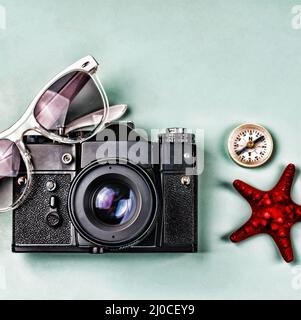 Alte Kamera, Kompass und Meer Souvenirs auf blauem Hintergrund. Stockfoto
