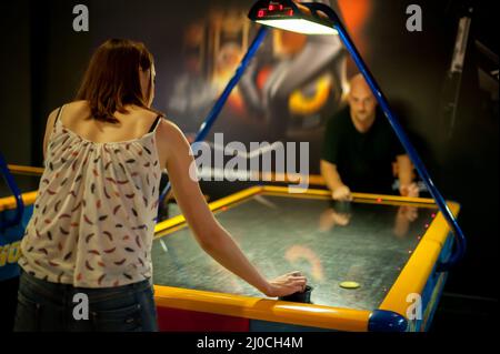 Junges Paar spielt ein Spiel des Air Hockey im Spielzimmer Stockfoto
