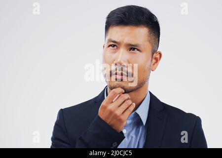 Einige Entscheidungen können Sie treffen oder brechen. Studioaufnahme eines Mannes, der vor grauem Hintergrund nachdenklich aussieht. Stockfoto