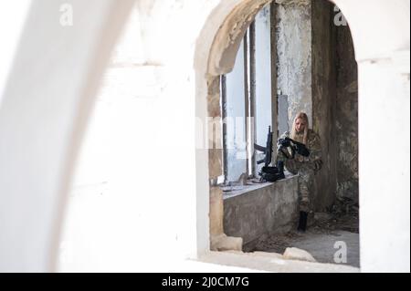 Kaukasische Militärfrau in einem zerstörten Gebäude. Stockfoto