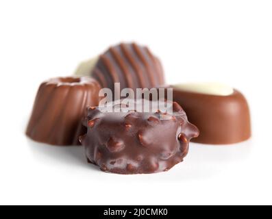 Verschiedene Pralinen oder Trüffel aus Schokolade. Nahaufnahme einer Vielzahl von kleinen, nicht einheitlichen Schokoladenbonbon, überzogen mit dunkler Schokolade und Milchschokolade Stockfoto
