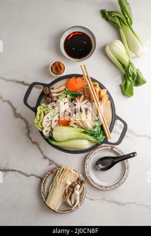 Sojamilch-Hot Pot-Rezept mit napa-Kohl, Pilzen und in dünne Scheiben geschnittenem Schweinefleisch, gekocht in einer cremigen und herzhaften Sojamilchbrühe. Stockfoto