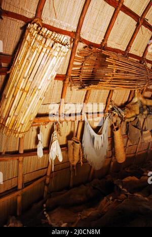 Tierhäute und Fischkörbe hängen an einem neu erfundenen Powhatan Longhouse Stockfoto