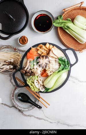 Sojamilch-Hot Pot-Rezept mit napa-Kohl, Pilzen und in dünne Scheiben geschnittenem Schweinefleisch, gekocht in einer cremigen und herzhaften Sojamilchbrühe. Stockfoto