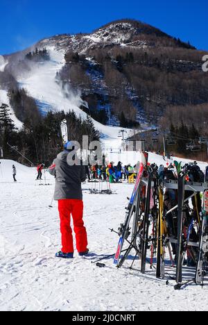 Ein Skifahrer nimmt seine Skier aus dem Regal, als er bereit ist, die Pisten zu befahren Stockfoto