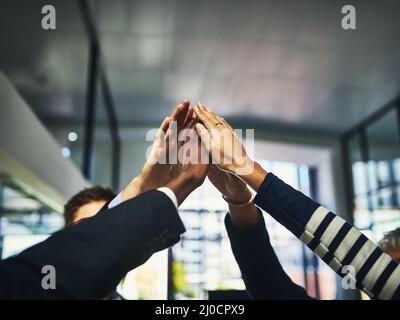 Schießen wir direkt auf einen weiteren Erfolg. Nahaufnahme einer Gruppe von nicht erkennbaren Geschäftsleuten, die in einem Büro hohe Fünffähigen. Stockfoto