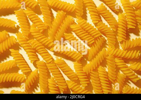 Spirale italienische Pasta oder Nudeln auf gelb von oben in einer flachen Lage Hintergrundstruktur betrachtet Stockfoto