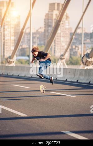 Skater macht Tricks und springt auf der Straßenautobrücke durch den Stadtverkehr. Freies Reiten Skateboard Stockfoto