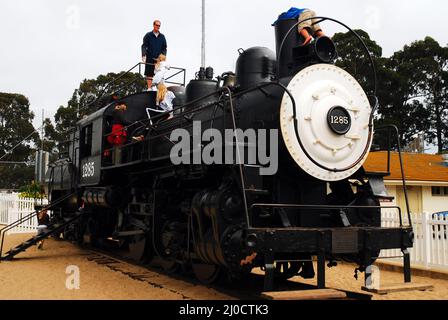 Kinder und Eltern spielen auf einem historischen Eisenbahnmotor in Monterrey, Kalifornien Stockfoto