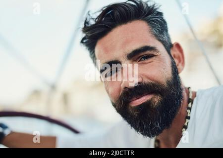 Bärtiger Kerl weiß, wie man chillen kann. Kurzer Schuss eines hübschen reifen Mannes auf seiner Yacht. Stockfoto