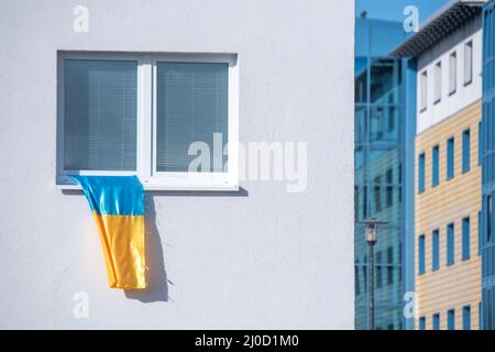 Greifswald, Deutschland. 18. März 2022. Eine ukrainische Flagge fliegt an einem Fenster in Greifswald. Quelle: Stefan Sauer/dpa/Alamy Live News Stockfoto