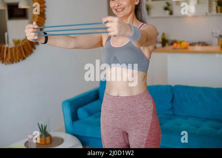 Fröhliche Frau, die zu Hause mit Fitnessgeräten trainieren kann Stockfoto