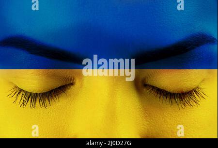 Frauengesicht in der ukraine-Flagge Farben. Ukraine Flagge über weiblichem Gesicht gemalt. Krisenkonzept der Ukraine Stockfoto