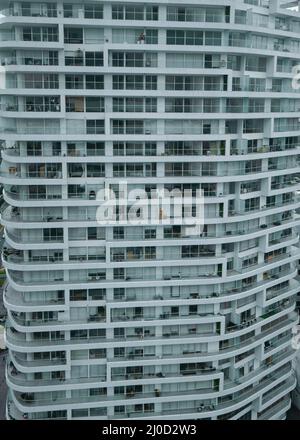 Die Struktur eines leeren weißen, modernen Gebäudes ist in der Nähe, ohne dass Menschen voller offener und geschlossener blauer quadratischer Fenster sind Stockfoto